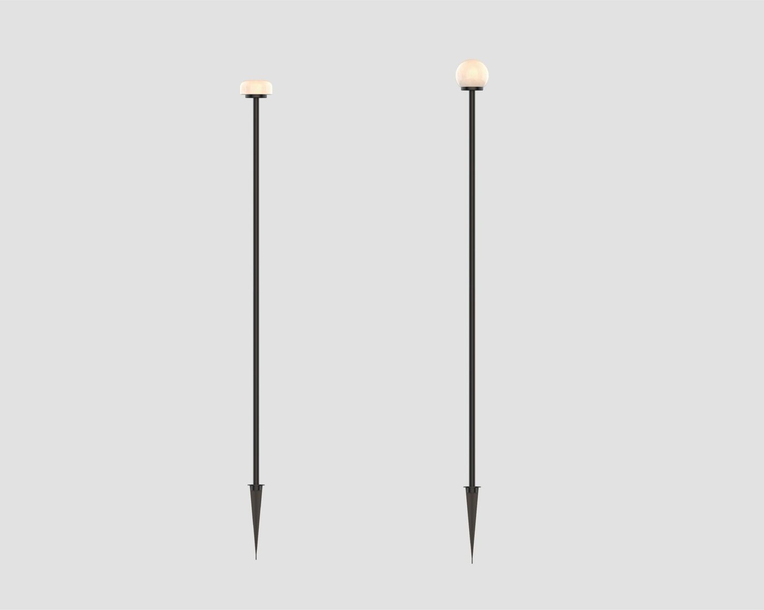 Two tall black street lamps with round white globes standing against a light gray background, spaced apart.