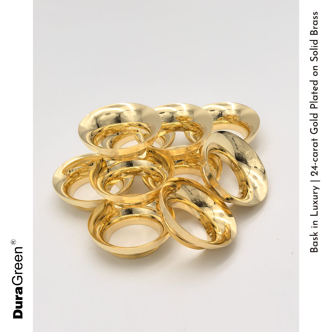 Pile of shiny gold-plated brass rings arranged on a white background, looking luxurious.