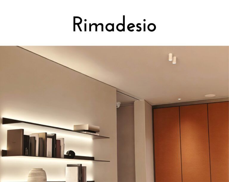 Showroom interior with display shelves and brown cabinetry under warm lighting; Rimadesio logo on a white wall above.