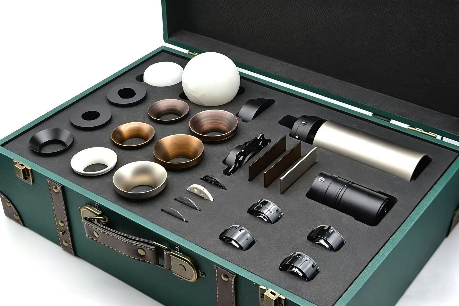 Open green case containing a set of metal lens rings, spacers, and small optical hardware laid in foam interior Alt text for an informative image.